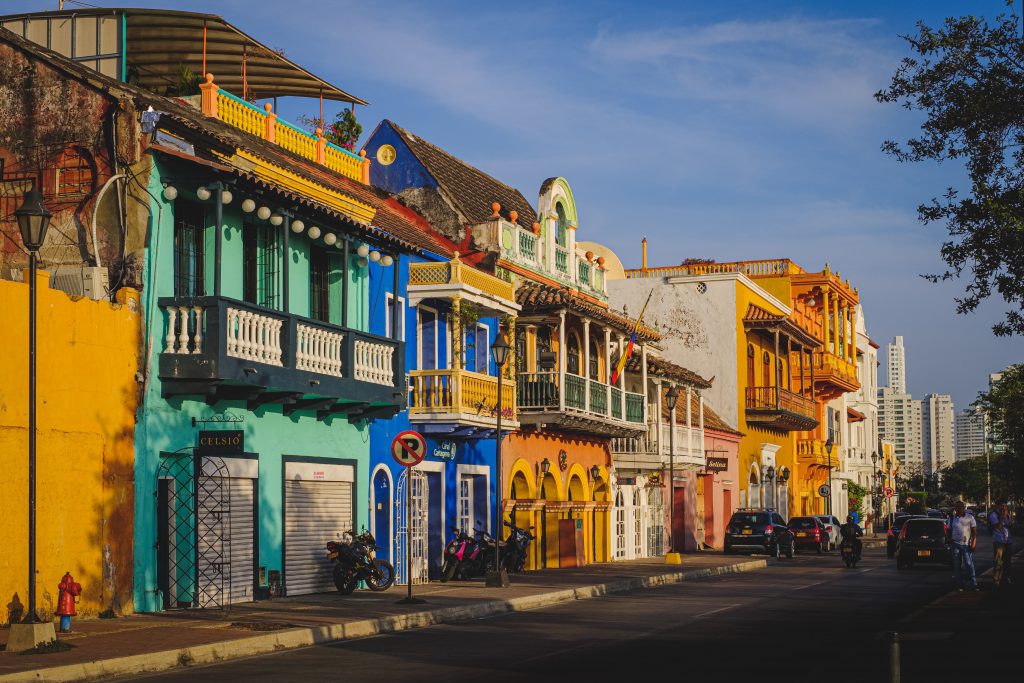 colorful buildings in turqoise, bright blue, orange, and yellow on a main street, Best Places to Visit in Colombia