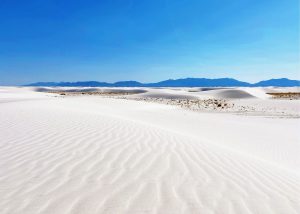 white sands national park, photo of white sand and mountains in the background under a bright blue sky