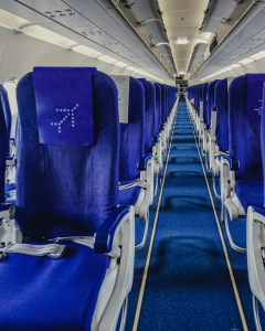 looking down empty airplane aisle lined with blue seats inside an airplane.